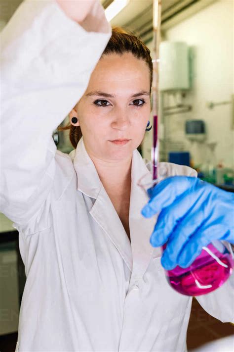 Concentrated Female Scientist In Medical Uniform Pouring Colorful