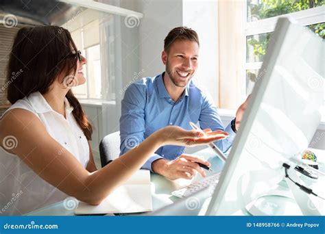 Two Businesspeople Looking At Computer Having Conversation Stock Photo