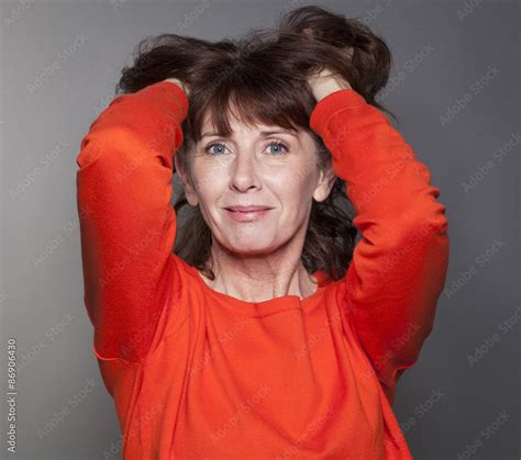 Radiant Mature Woman Playing With Her Hair Wearing Colorful Sweater Expressing Wellbeing And