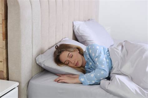 Young Woman Sleeping In Comfortable Bed With Silky Linens Stock Photo