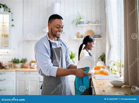 Cheerful Black Woman Washing Dishes While Her Husband Wiping Them At