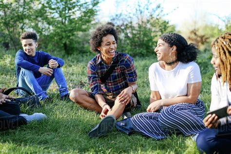 Group Of Friends Sitting On Grass Laughing Stock Photo Dissolve