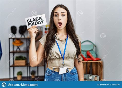 Young Brunette Woman Holding Black Friday Banner At Retail Shop Scared