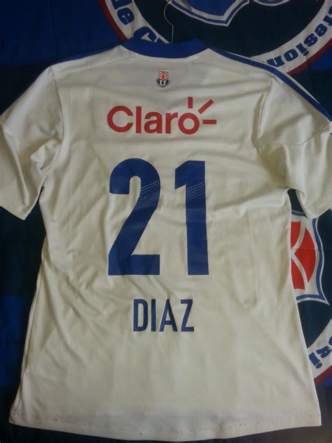 Com detalhes gráficos subtis e gola em v, é finalizada com o badge of sport no peito e com o brasão da equipa. Universidad de Chile Visitante Camiseta de Fútbol 2012.