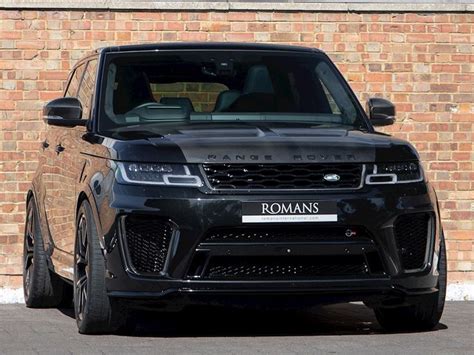 A Black Range Rover Parked In Front Of A Brick Wall With The Name