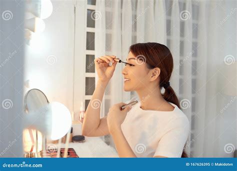 Beautiful Asian Woman Applying Mascara For Her Eyelashes Stock Image