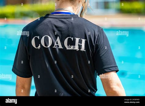 Back View Of Female Swimming Coaches Wearing Coach Shirt Working At