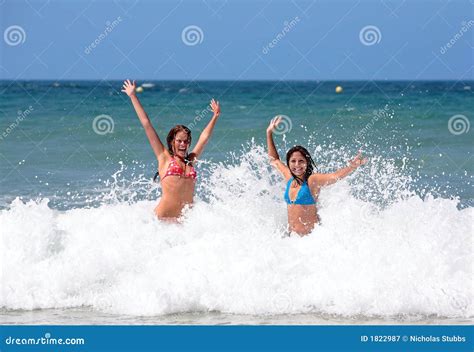 Two Attractive Young Girl Friends Playing In The Sea On Vacation Stock