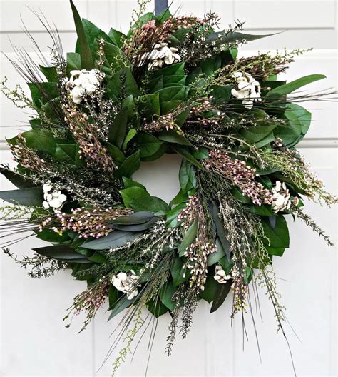 Two cups of healthy herbal tea with mint, cinnamon, dried rose and camomile flowers in spoons over blue background. Dried flower wreath is made with preserved foliage and ...