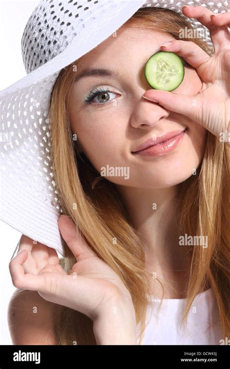 Portrait Of Young Adult Caucasian Woman On White Background Holding Cucumber Slices Over Her