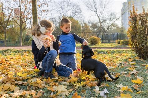 dzieci chłopiec i dziewczynka bawi się z psem jamnika zdjęcie premium