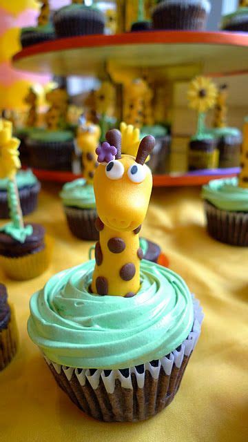 Cupcakes With Giraffe Decorations On Them Sitting On A Yellow Tablecloth