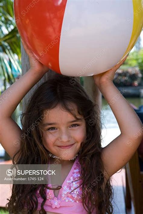 Portrait Of A Girl Holding A Beach Ball Superstock