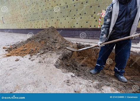 Worker With Shovel Is Digging A Pit On Construction Site Concept Of