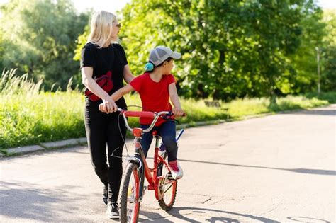Belle Et Heureuse Jeune Mère Apprenant à Sa Fille à Faire Du Vélo Les Deux Souriants Parc D