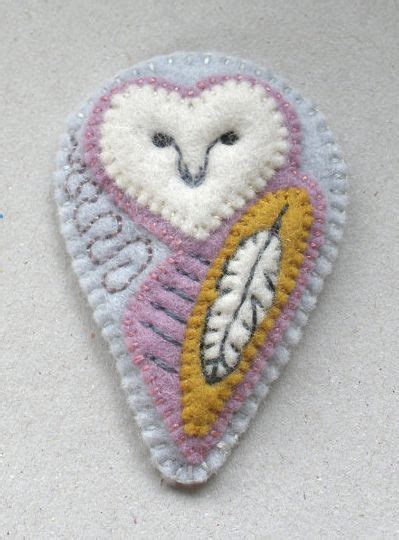 An Embroidered Brooch With A White And Pink Owl On Its Back Side