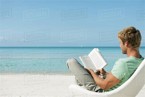 Young Man Reading Book On Beach Stock Photo Dissolve