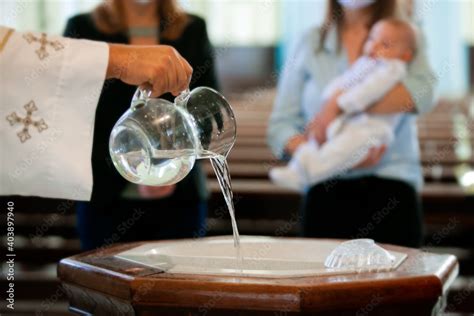 Priest Pouring Holy Water Into The Baptismal Font Moments Before A