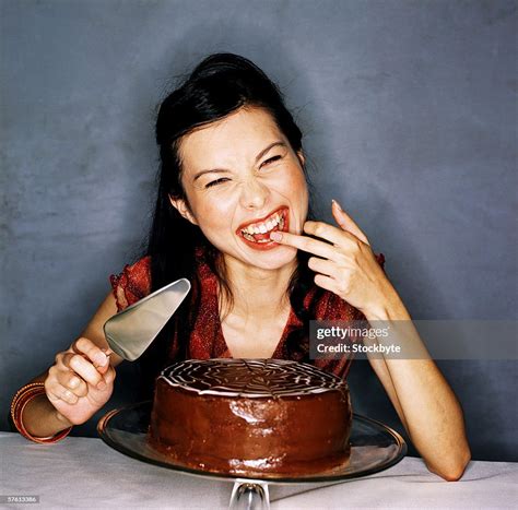 Closeup Of A Woman Licking Chocolate Icing Off Her Finger High Res