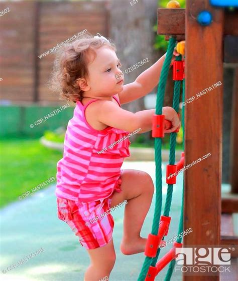 Small Girl Child Climbing Up On Children Activity Ladder Outdoors