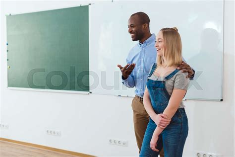 Smiling African American Teacher Introducing New Girl In Classroom