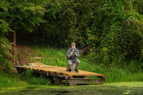 A Man Sits On A Wooden Boat Dock On A Forest Lake Stock Photo Image