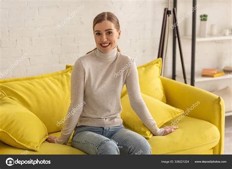 Hermosa Chica Sentada Sofá Sala Estar Sonriendo Cámara Fotografía De Stock © Andrewlozovyi