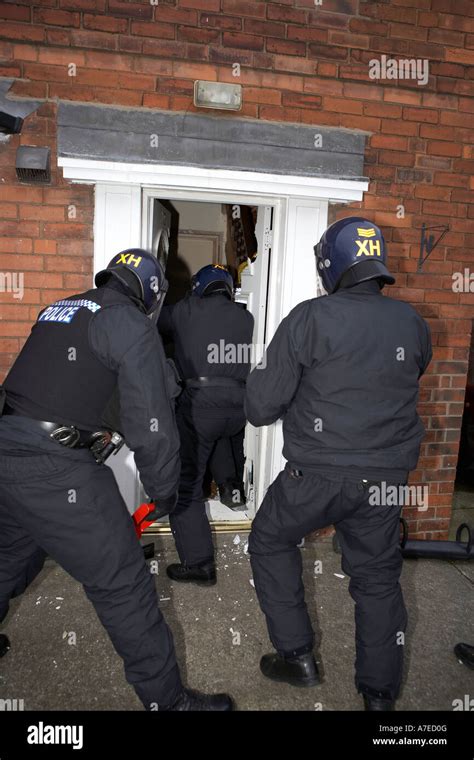 Police Enter A House After Breaking Down A Front Door During A Raid On Suspected Drugs Dealers