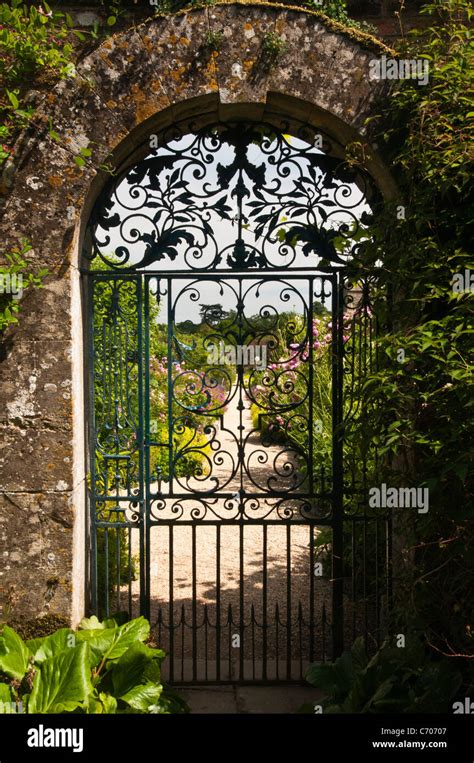 Ornate Wrought Iron Gate Set In A Cotswold Stone Archway Leads To The