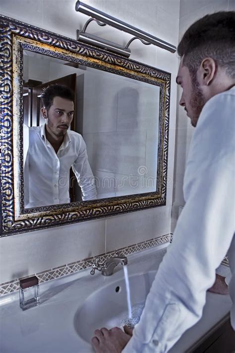 A Man Standing In Front Of A Bathroom Mirror
