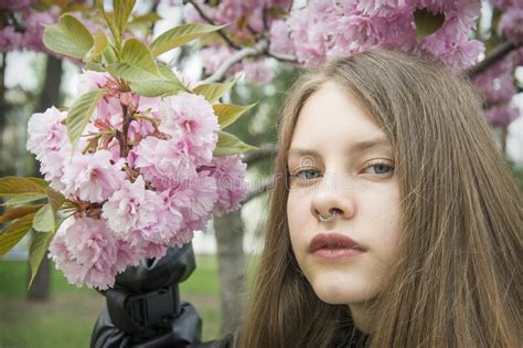Young Girl Posing Near Blossom Cherry Tree With Pink Flowers Stock
