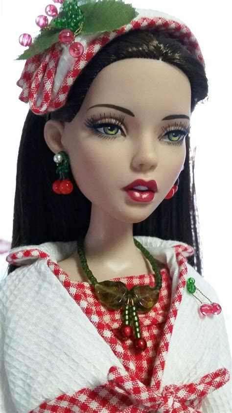 A Doll Wearing A Red And White Checkered Dress With Green Accents On Her Head
