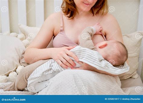Woman Mother Breastfeeds Infant Baby Boy Sitting On Home Bed Mom Feeds