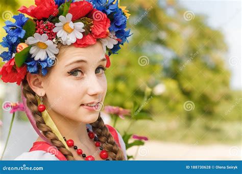 Close Portrait Of Girl With Two Braids In Ukrainian Traditional Flowers Wreath With Ribbons Red