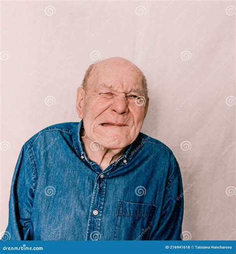 A Cheerful Old Man With Wrinkles Grimaces And Makes Faces On A White