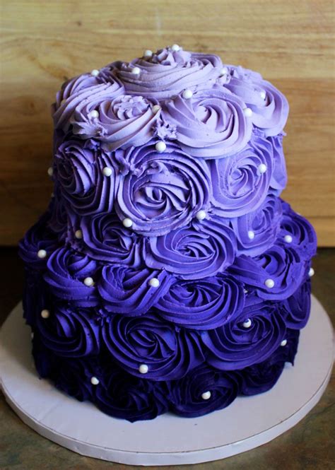 There Is A Purple Cake With White Flowers On It And Pearls Around The