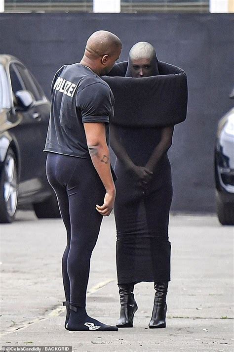 Two Men In Black Bodysuits Standing Next To Each Other On The Street
