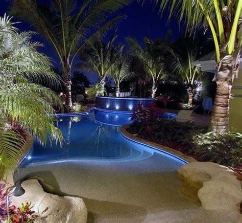 An Outdoor Swimming Pool Surrounded By Palm Trees And Landscaping At