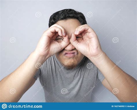 Young Man Making Telescope Gesture With His Hand Stock Photo Image Of