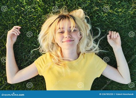 Top View Of A Beautiful Teenage Blonde Lying On The Green Grass Stock