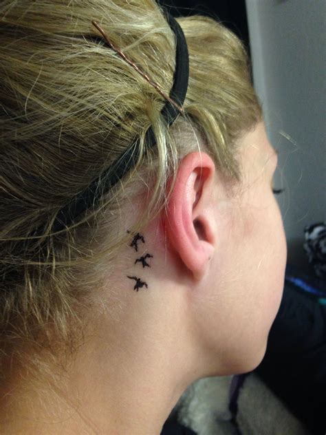 A Womans Behind The Ear Tattoo With Three Small Birds On Her Left Side