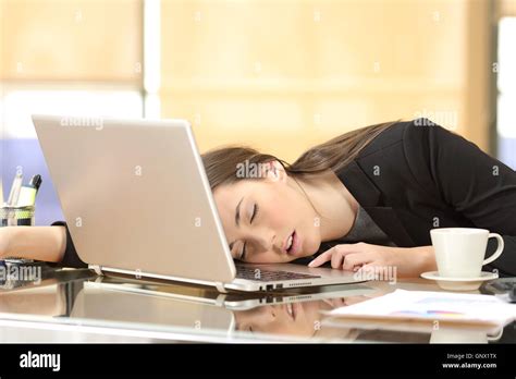 Overworked And Tired Businesswoman Sleeping Over A Laptop In A Desk At Work In Her Office Stock