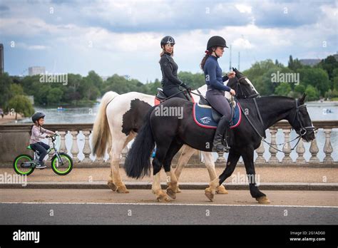 Two Horse Riders Cross A Bridge Over The Serpentine In Hyde Park