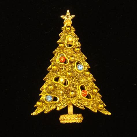 A Gold Christmas Tree Brooch With Multi Colored Stones In The Shape