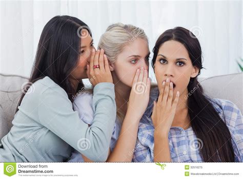 Two Friends Whispering Secret To Shocked Brunette Stock