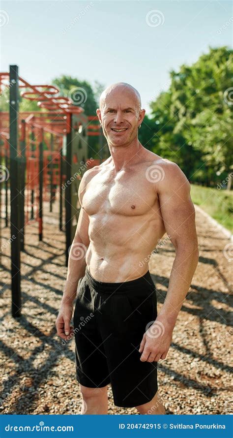 Athletic Mature Man Bodybuilder With Naked Torso Smiling At Camera Posing Outdoors While