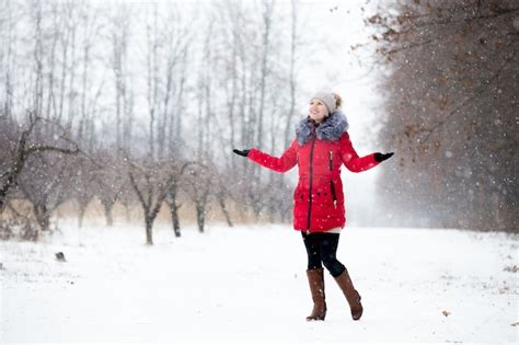 feliz sonriente mujer en chaqueta de invierno rojo disfruta de la nieve al aire libre en el