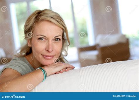 Mujer Madura Rubia Que Se Inclina En La Sonrisa Del Sofá Imagen De