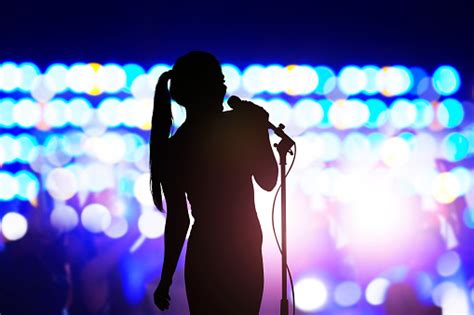 Silhouette Of Woman With Microphone Singing On Concert Stage In Front