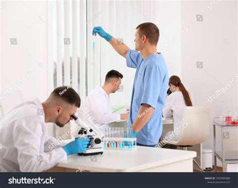 Scientist Using Microscope Table Colleagues Laboratory Stock Photo